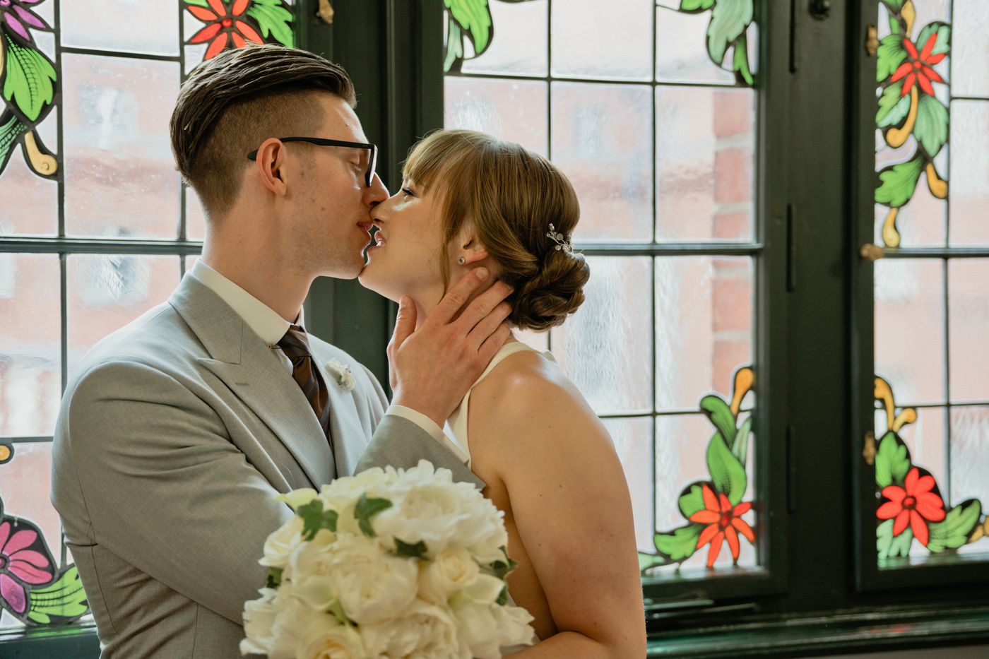 Brautpaar küsst sich vor bunten Glasfenstern – Hochzeitsfotografin Elisa, Berlin & Brandenburg